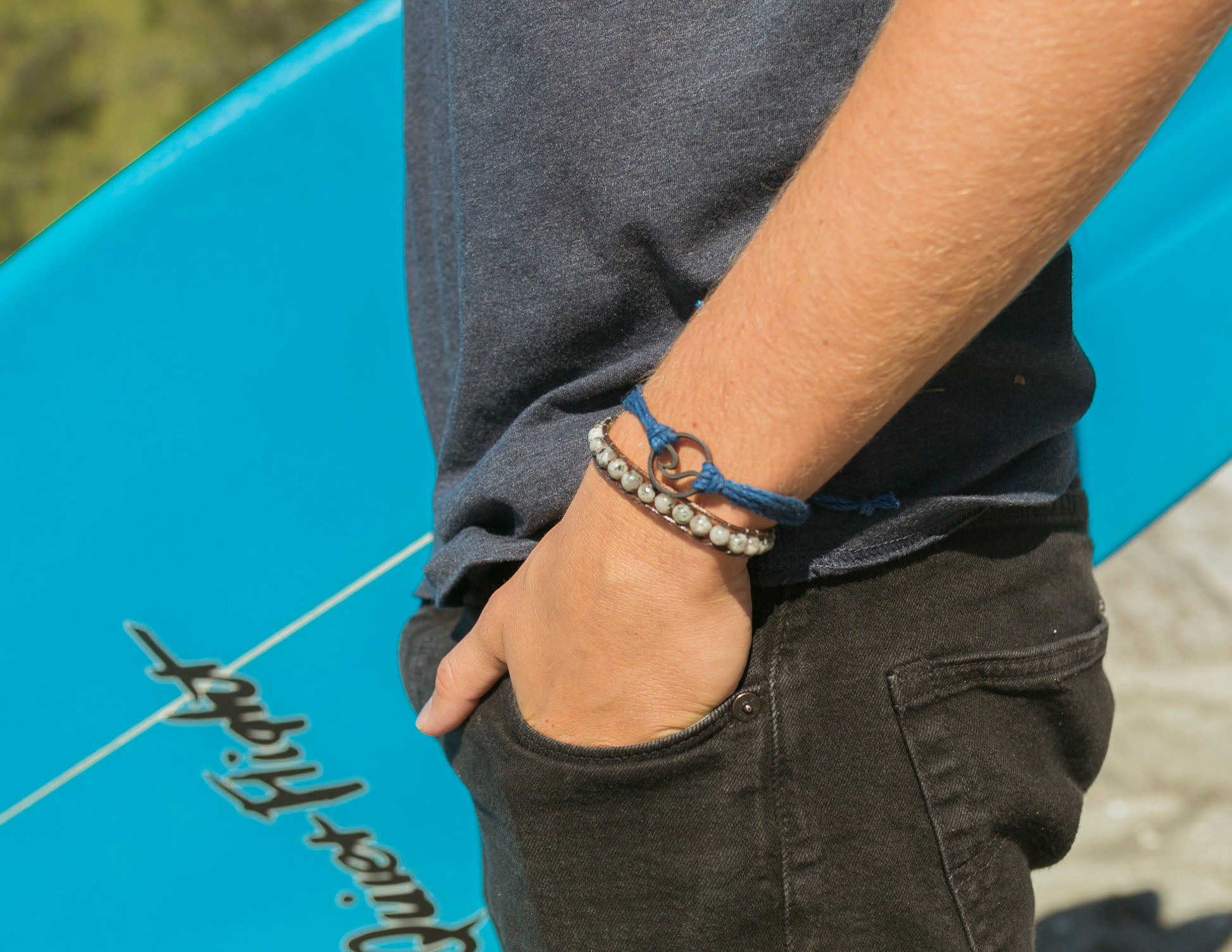 surfer wearing black wave pura vida string bracelet 